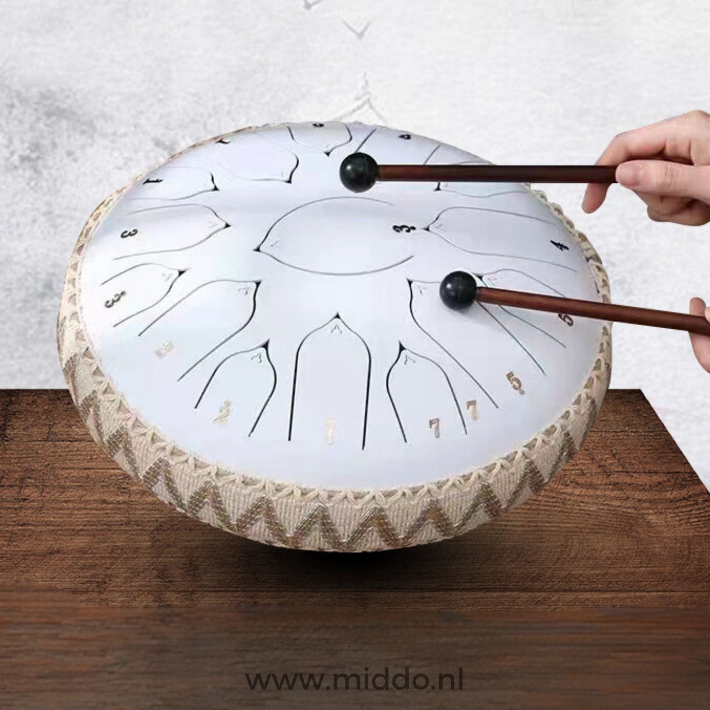 Handen bespelen een witte Harmonii KlankOase Steel Tongue Drum met mallets